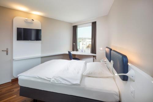 a hotel room with a white bed and white walls at Hotel Welcome Inn in Kloten