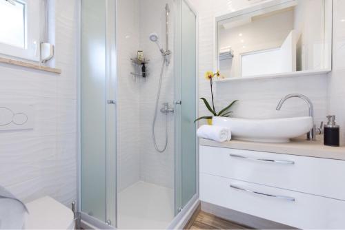uma casa de banho com uma cabina de duche em vidro e um lavatório. em Apartman Fortica em Opatija