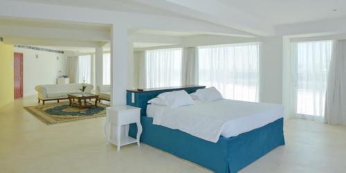 a bedroom with a blue bed and a living room at Ibiscus Hotel in Rhodes Town