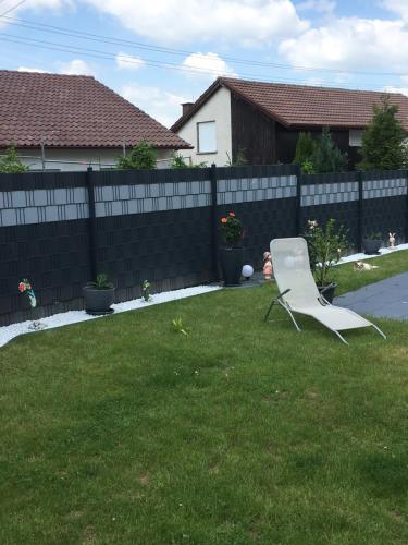 a white chair sitting in a yard next to a fence at Herz der Weinberge in Gemmrigheim