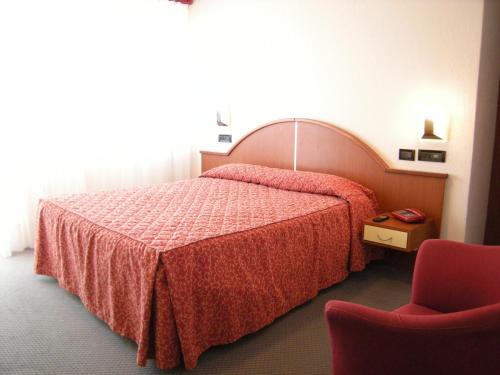 AlbinoにあるAlbergo Valle d'Oroのベッドと椅子付きのホテルルーム