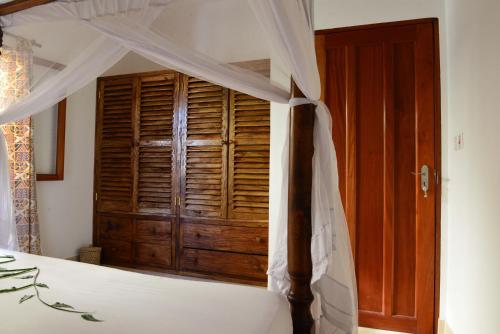 a bedroom with a canopy bed with a wooden door at Rafiki Village in Watamu