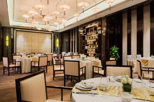 a dining room with white tables and chairs at Wanda Realm Nanjing in Jiangning