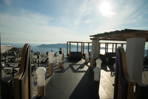 a balcony with tables and chairs and the sun at Galaxy Suites & Villas in Imerovigli