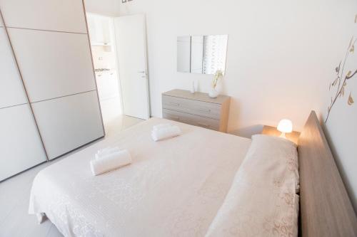 a white bedroom with a bed and a mirror at Le Zagare in Lascari