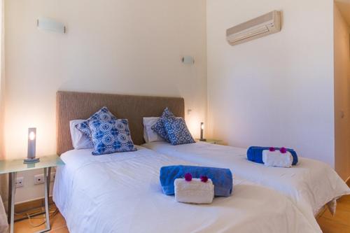 um quarto com 2 camas com almofadas azuis e brancas em Boa Vida em Quarteira