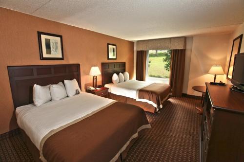 a hotel room with two beds and a television at Baymont by Wyndham Branson - On the Strip in Branson