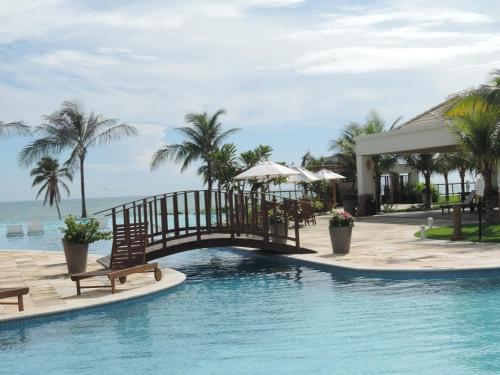 einen Pool in einem Resort mit einer Brücke und Palmen in der Unterkunft Apartamento Waiwai Cumbuco in Cumbuco