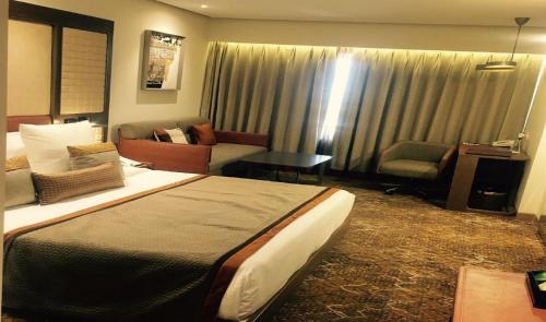 a hotel room with a bed and a couch at Sayaji Indore in Indore