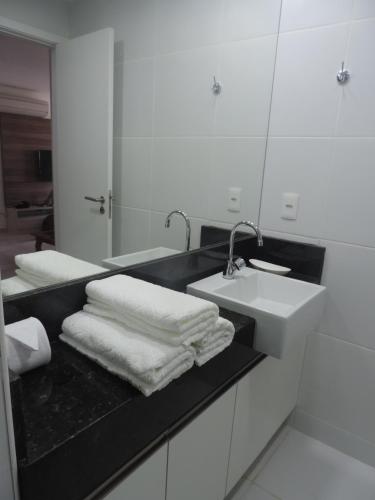 a bathroom with a sink and a mirror and towels at Apartamento Waiwai Cumbuco in Cumbuco