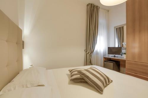 a bedroom with a white bed with two pillows at Hotel Il Buongustaio in Massa