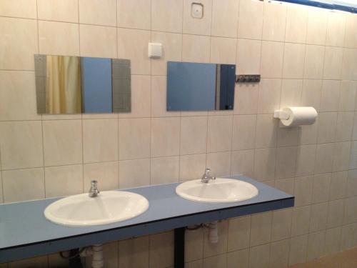 a bathroom with two sinks and two mirrors at Domki Letniskowe Vertigo Narie in Morąg