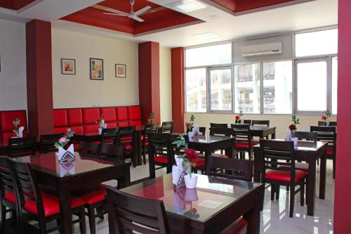 a dining room with tables and chairs and windows at Hotel Shikhar & Restaurant in Almora