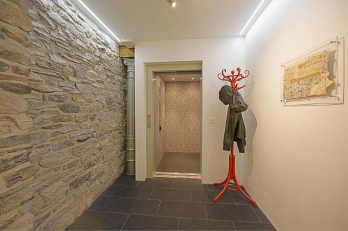 a hallway with a stone wall and a statue on a red stand at Alplodge in Interlaken