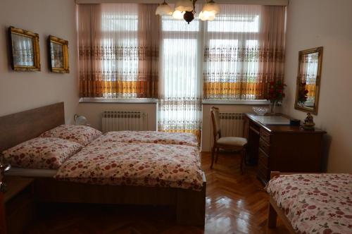 een slaapkamer met 2 bedden, een bureau en ramen bij Apartment Sarah in Bihać