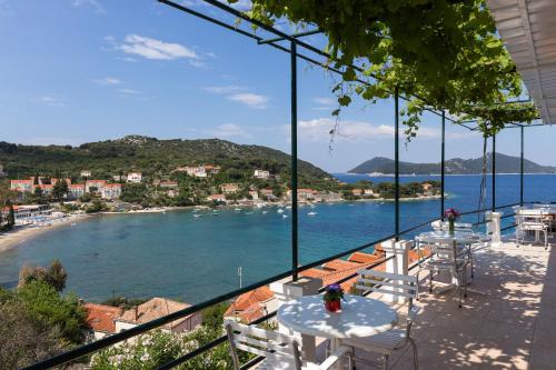 a balcony with tables and chairs and a view of a beach at Apartments Miskovic in Koločep