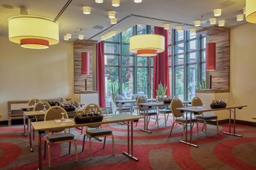 a dining room with tables and chairs and large windows at H+ Hotel Bad Soden in Bad Soden am Taunus