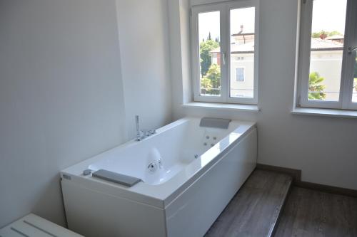 a white bathroom with a large tub and two windows at Grand Hotel Liberty in Riva del Garda