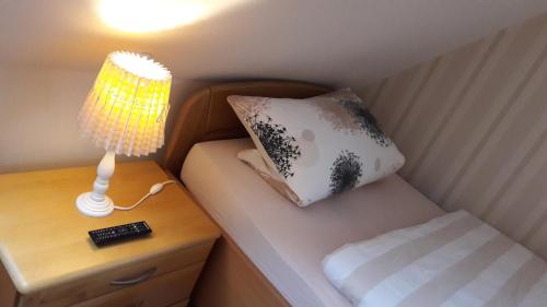 un piccolo letto con lampada e cuscino su un comodino di Gästezimmer Grimmelmann a Eystrup