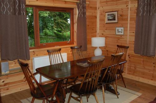 jadalnia ze stołem i krzesłami w kabinie w obiekcie Fir Tree Lodge w mieście Blairgowrie