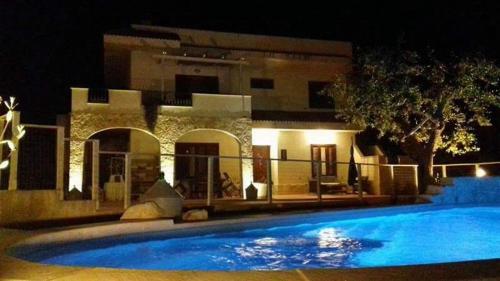 a large swimming pool in front of a building at night at B&B Villa Nonna Maria in Castellana Grotte