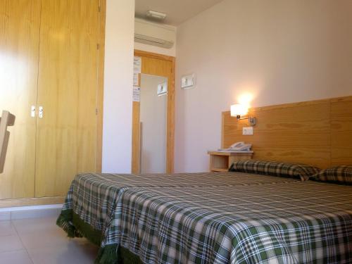 una camera d'albergo con un letto con una coperta a quadri di Pensión Balcones Azules a Cartagena