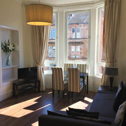 a living room with a table and chairs and windows at Trefoil Apartment - 2 Bedrooms in Glasgow
