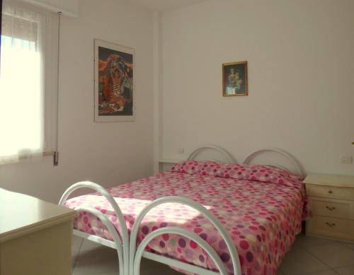 een slaapkamer met een bed met een roze dekbed bij Appartamenti Vittoria in Lido di Pomposa