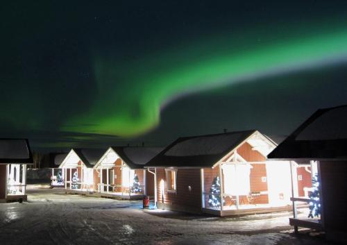 a row of houses with the aurora in the sky at Santa Claus Holiday Village in Rovaniemi