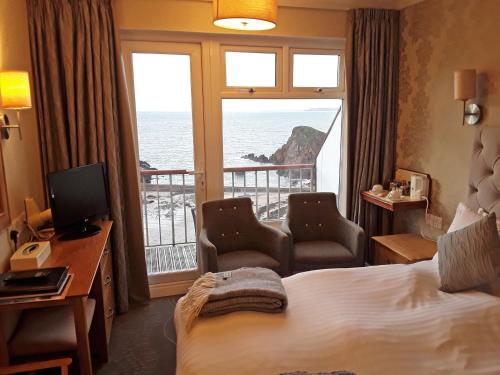 a hotel room with a bed and a view of the ocean at The Cottage Hotel in Hope-Cove