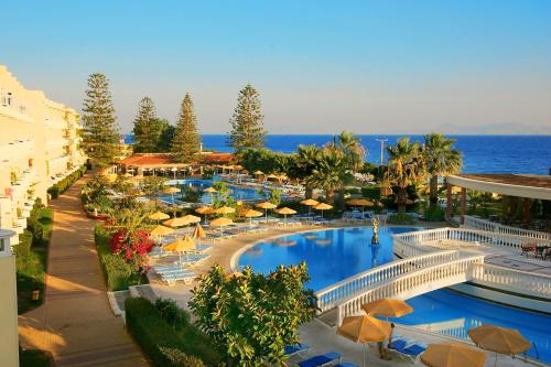 un complexe avec une piscine entourée de parasols et l'océan dans l'établissement Sunshine Rhodes, à Ialyssos