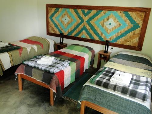 a room with three beds with colorful blankets at Pousada Do Pequi in São Gonçalo do Rio das Pedras