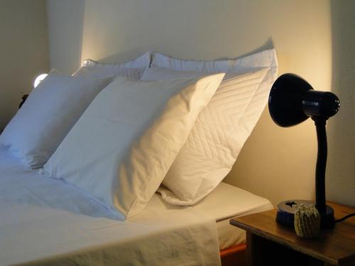 a bed with white pillows and a lamp on a table at Pousada Do Pequi in São Gonçalo do Rio das Pedras