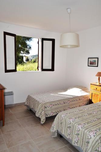 deux lits dans une chambre avec une fenêtre dans l'établissement le relais de tiuccia, à Casaglione