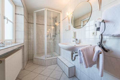uma casa de banho branca com um lavatório e um chuveiro em Hotel Neudeck em Oberstaufen