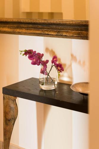a vase of flowers on a table in front of a mirror at Villa Le Terrazze Charming Rooms in Taormina