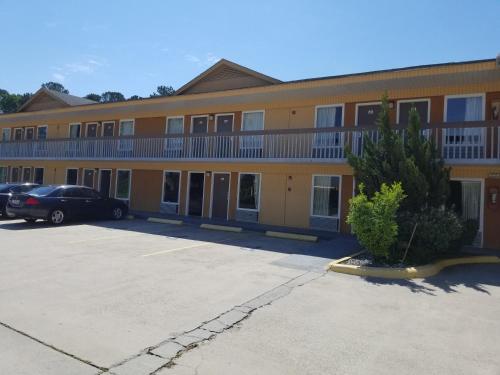 un grand bâtiment avec une voiture garée dans un parking dans l'établissement Americas Best Inn - Savannah I-95, à Savannah