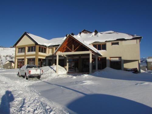 a house with a car parked in the snow at Hotel Nitra-Caviahue in Caviahue