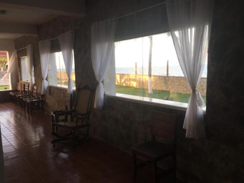 a room with chairs and windows with a view of the ocean at Beach Hotel Jacuma in Jacumã