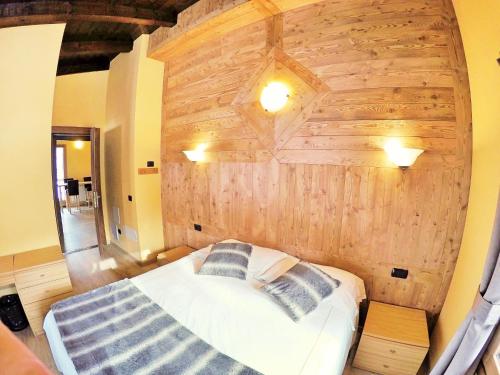 a bedroom with a bed with a wooden wall at Chalet Alpina Hotel & Apartments in La Thuile
