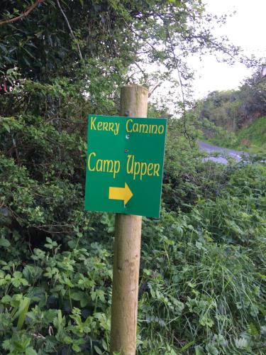 a green sign on a pole next to a road at Coach Field Camp in Camp