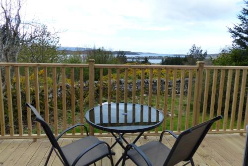a patio with a table and chairs on a deck at Aultbea Lodges in Aultbea