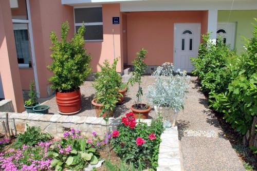 a garden with potted plants and flowers in front of a building at Apartment Bura in Šibenik