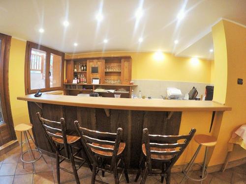 a kitchen with a bar with chairs around it at Chalet Alpina Hotel & Apartments in La Thuile