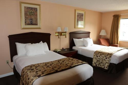 una habitación de hotel con 2 camas y una silla en American Elite Inn, en Hazard