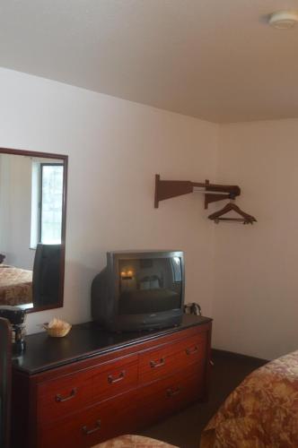 a room with a tv on a dresser with a mirror at American Elite Inn in Hazard