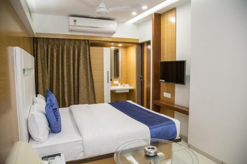 a hotel room with a bed and a tv at Hotel Orange International in Surat