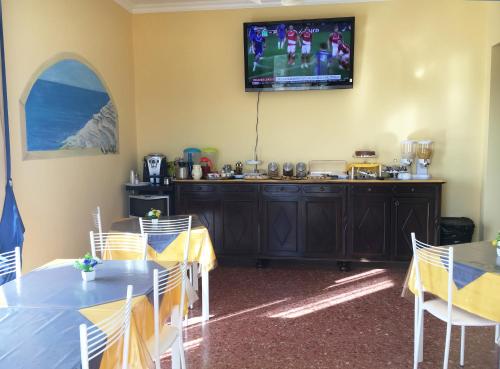 a room with tables and a television on a wall at La Città degli Dei in Agrigento