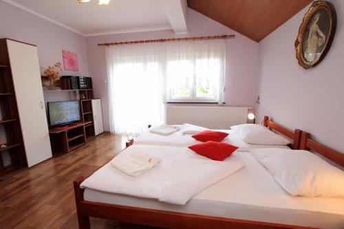 a bedroom with a large white bed with red pillows at Vila Julija - Apartment & rooms in Otočac
