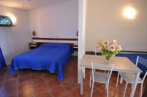 a bedroom with a bed and a table with a vase of flowers at Appartamenti I Lauri in Porto Azzurro